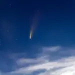 bright comet in night sky over European landscape
