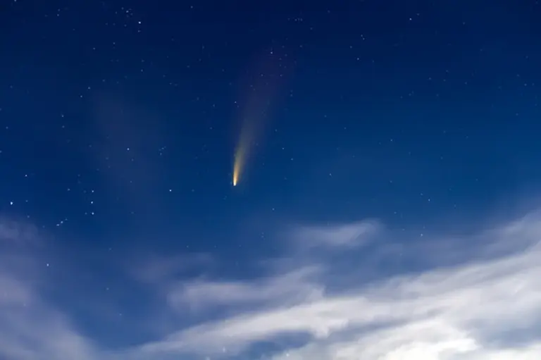 bright comet in night sky over European landscape