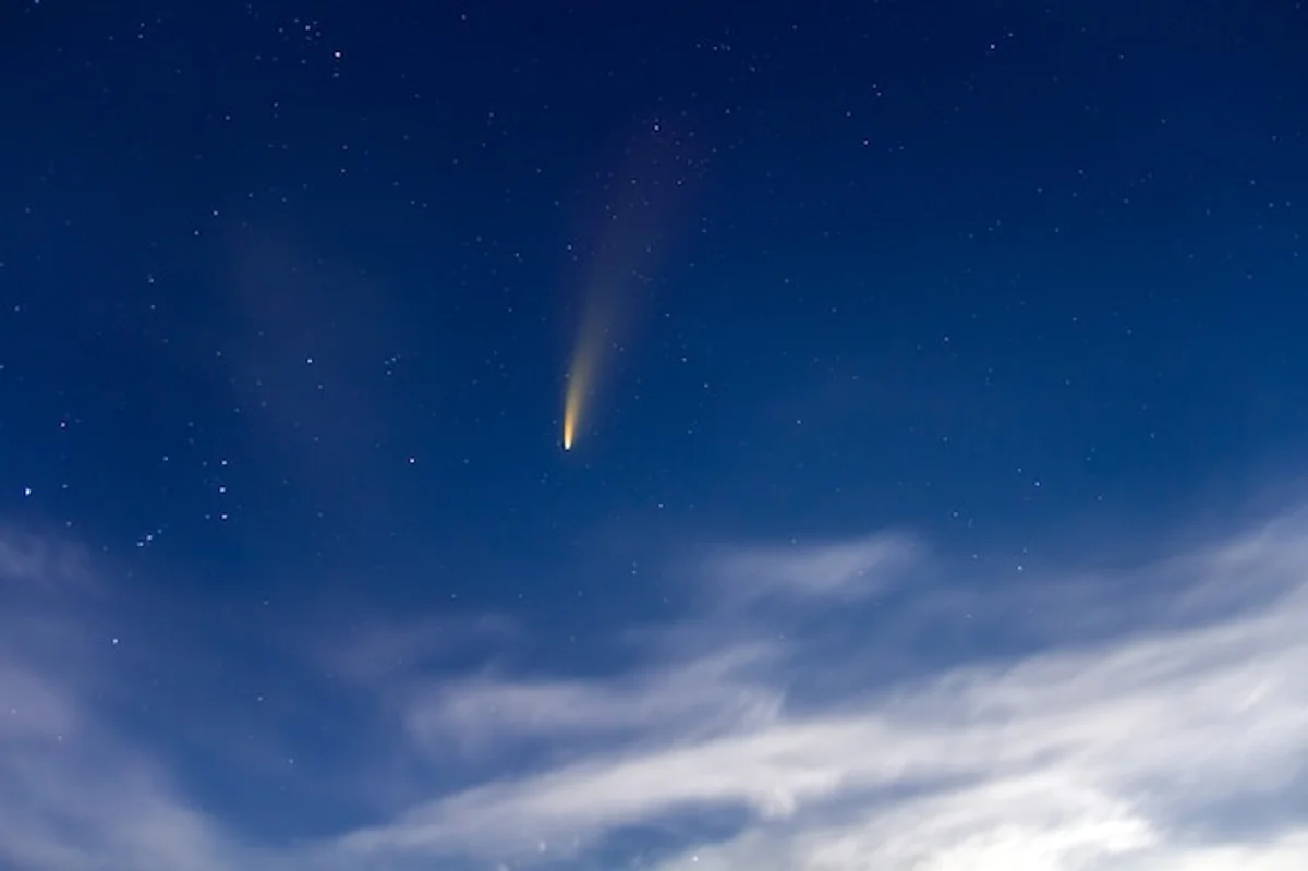 bright comet in night sky over European landscape