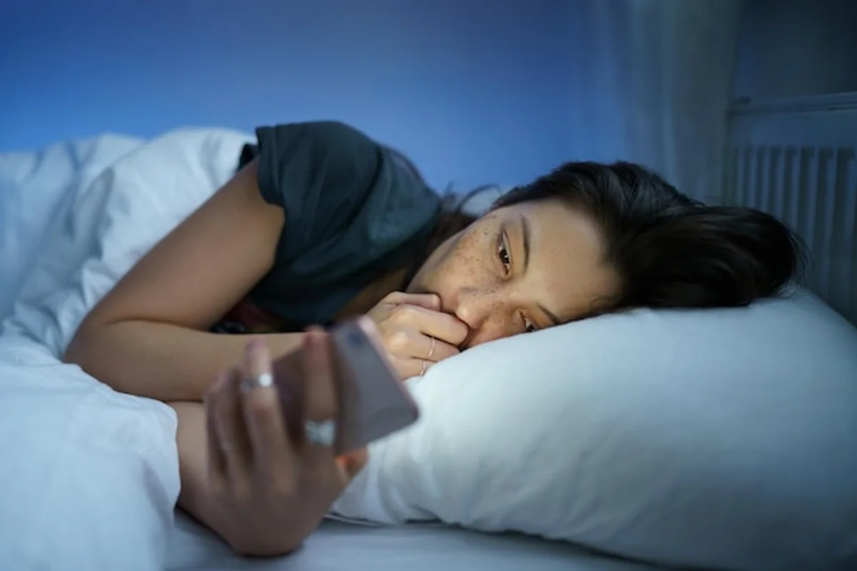 woman scrolling social media at night in bed, insomnia