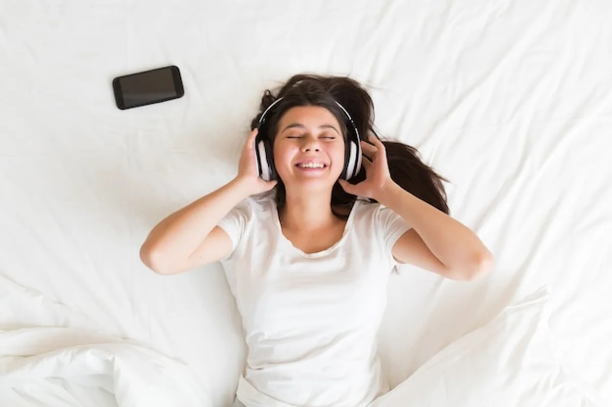 relaxed person lying with closed eyes listening to music at home