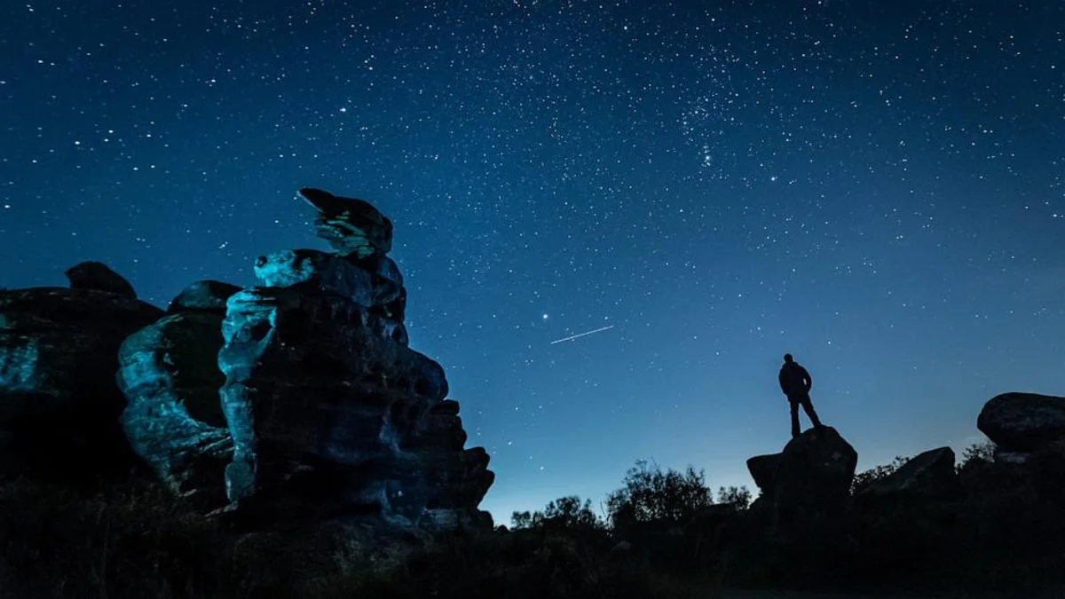 person watching orionids meteors with blanket in night landscape